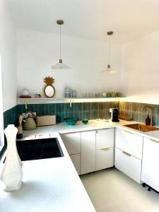 a kitchen with white cabinets and green tiles at Appartement au port de Dinan Belle île in Dinan