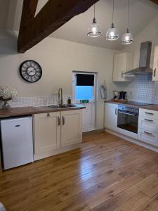 a kitchen with white cabinets and a wooden floor at Hayloft studio apartment in Warwick