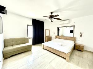 - une chambre avec un lit, un canapé et un ventilateur de plafond dans l'établissement וילות היוקרה עידן הנוף ואחוזת אסתובן, à Ya‘ara 13 autres photos