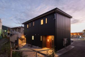 a black house with lights on the side of it at YUFU-Inn プライベートな露天風呂付き-由布院駅徒歩2分 in Yufuin