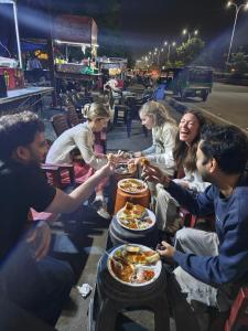 a group of people sitting around a table eating food at Hammock Hostels - Jaipur in Jaipur