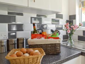 a basket of eggs and bottles of wine on a kitchen counter at The Duck House in Ruckinge