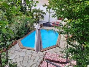 a swimming pool with an umbrella and two chairs at Villino Bianca in Trisobbio