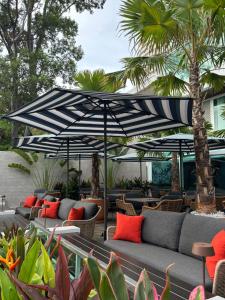 a patio with couches and umbrellas and palm trees at Gooseberry Baan & Bistro in Pattaya South