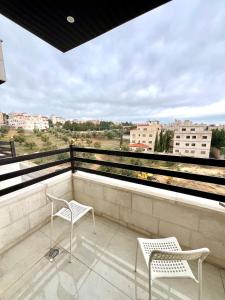 two chairs on a balcony with a view at Ammon Sun Residence in Amman