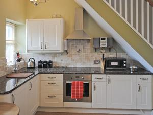 a kitchen with white cabinets and a stove top oven at Cobweb Cottage in Whitby