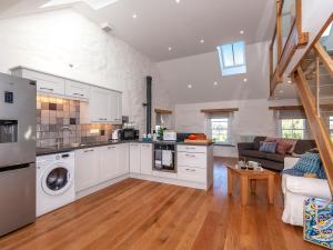 a kitchen with white cabinets and a living room at The Loft - Cottage in Letterston