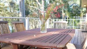 einen Holztisch mit einer Blumenvase auf dem Deck in der Unterkunft Hardys Bay View From Every Window in Hardys Bay + 31 Fotos