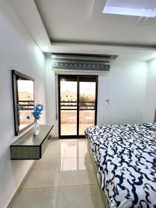 a bedroom with a bed and a table and windows at Ammon Sun Residence in Amman