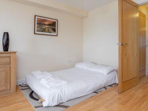 a bedroom with a bed with white sheets and a mirror at 6 Harbour View in Newquay