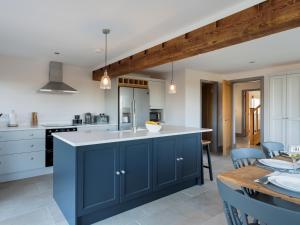 a large kitchen with blue cabinets and a table at The Maddocks - Uk36311 in Whitchurch