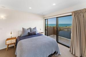 a bedroom with a bed and a view of the ocean at Kaiteriteri Luxury Apartment in Kaiteriteri +17 photos