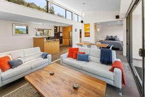 a living room with two white couches and a bedroom at Kaiteriteri Luxury Apartment in Kaiteriteri