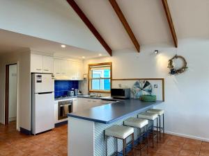 a kitchen with a counter with stools and a refrigerator at Dunes Blue at Robe in Robe