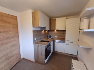 cocina pequeña con armarios blancos y fogones en Panoramahof Gupf, en Gröbming 96 fotos más