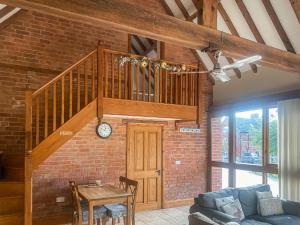 sala de estar con escalera y pared de ladrillo en The Old Carthouse, en Abbots Bromley