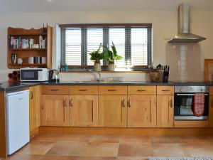 een keuken met houten kasten en een witte koelkast bij The Wests in Lastingham