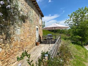 a wooden deck with a table and an umbrella at la cachette bas in Salies-de-Béarn
