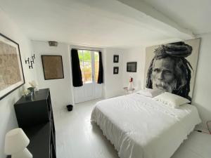 a white bedroom with a portrait of a man on the wall at la cachette bas in Salies-de-Béarn