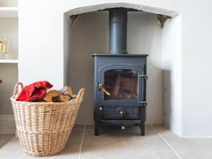 Easton on the HillRed Kite Cottage的一个带篮子的房间的黑炉子