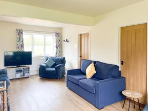 een woonkamer met twee blauwe stoelen en een televisie bij Old Alton Hall Farmhouse in Tattingstone