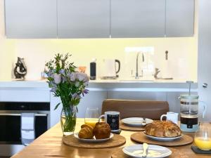 a table with plates and croissants and a vase of flowers at The Sail Loft - Royal William Yard in Millbrook