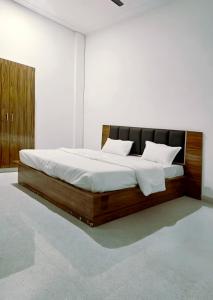 a bedroom with a wooden bed with white sheets at Hotel Sanjay palace in Mahwah