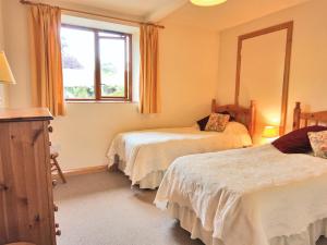 a bedroom with two beds and a window at Bridle Cottage in Hoarwithy