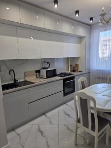 Una cocina con gabinetes blancos y una mesa con sillas. en Транзит Сервис 3 Аэропорт- Кишинёв, en Chişinău 29 fotos más