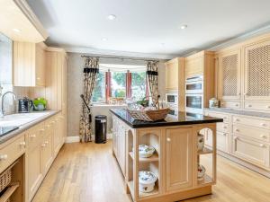 Una cocina con gabinetes de madera y una encimera negra. en The Hawthorns, en Ottringham 20 fotos más