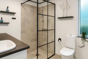 a bathroom with a shower with a toilet and a sink at Strandhuset i Øster Hurup in Øster Hurup +17 photos