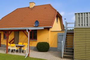 a yellow house with a table and chairs on a patio at Strandhuset i Øster Hurup in Øster Hurup