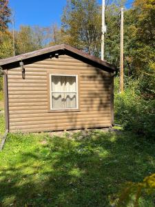 a small building with a window in the grass at Pennsylvania Glamping Destination for Nature Getaways for Four in Charming Log Cabin in Germania