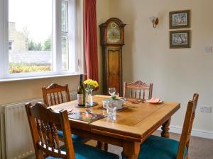 a wooden table with a grandfather clock in a dining room at Belgravia Cottage in Skipton