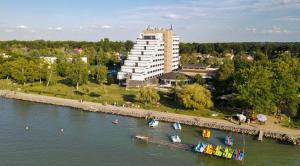 a building next to a river with boats in the water at Premium Hotel Panoráma in Siófok