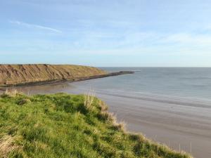 a beach with the ocean in the background at The Parade Apartment in Reighton