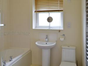 a bathroom with a sink and a toilet and a window at The Parade Apartment in Reighton