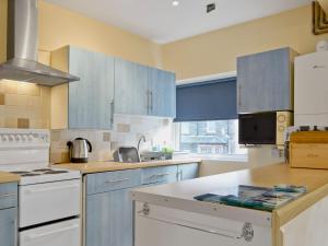 a kitchen with blue cabinets and white appliances at Serendipity in Keswick