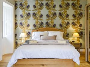 a bedroom with a large bed with a floral wallpaper at Riverside Cottage in Blair Atholl