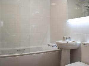a white bathroom with a sink and a bath tub at 15 Elm Court in Keswick
