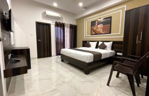 a bedroom with a bed and a chair in it at Hotel Yashoda Palace in Kota