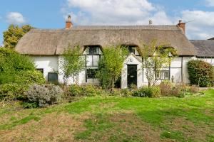 ein altes weißes Cottage mit einem Strohdach in der Unterkunft Beautiful 5-Bedroom Home with Cinema & Games Room 