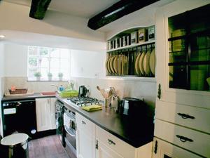 eine Küche mit weißen Schränken und einer schwarzen Arbeitsplatte in der Unterkunft The Little Stone Cottage in Loftus
