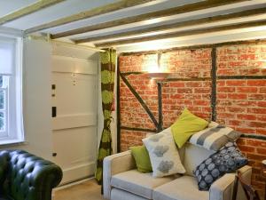 ein Wohnzimmer mit einer Couch und einer Ziegelwand in der Unterkunft Rose Cottage in Hythe