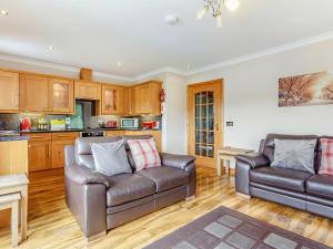 a living room with two leather couches and a kitchen at Carinish Beag in Achaphubuil
