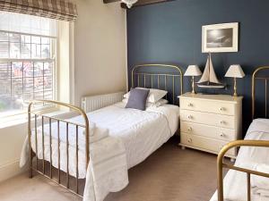 a bedroom with a bed and a dresser and a window at Seacrest Cottage in Whitby