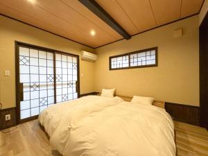 a bedroom with a large white bed with two windows at Ryokan YUFUMOMIJI in Yufuin