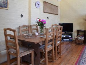a wooden table with chairs and a vase of flowers on it at Brook Barn in Ellingham
