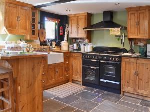 a kitchen with wooden cabinets and a black stove at Brook Barn in Ellingham