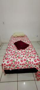 a bed with a flowered comforter on the floor at Casa do sossego - conforto, praia, piscina in Maricá